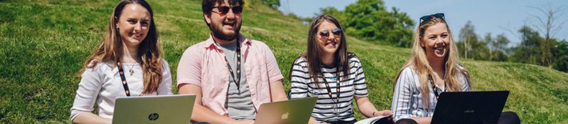 Young people with laptops sat outside