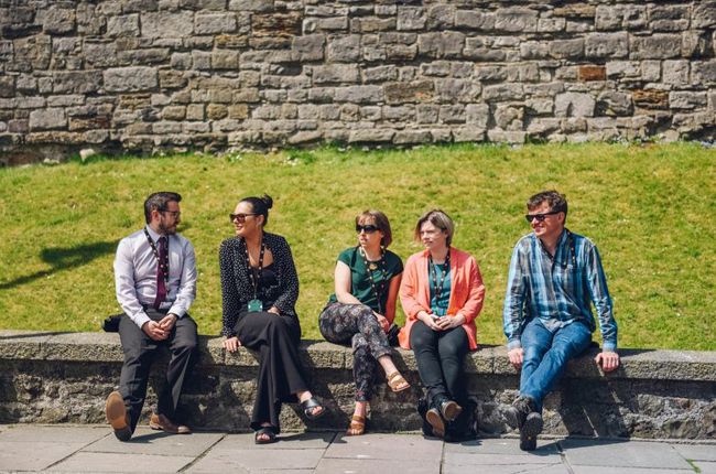 Five people sitting on wall during lunch hour