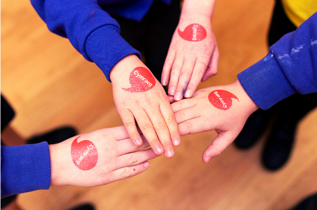 Iaith Gwaith logo on children's hands